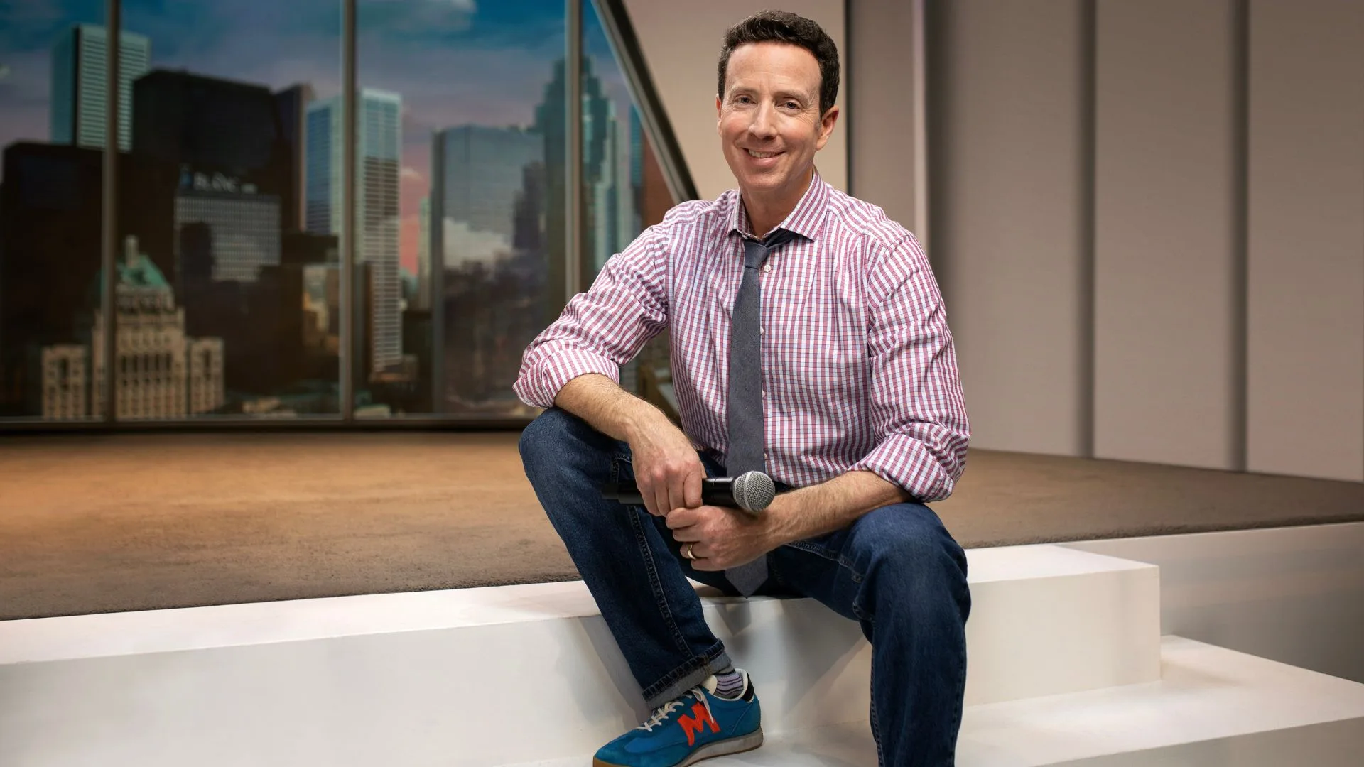 Adam Growe seated on a studio stage with the Toronto skyline